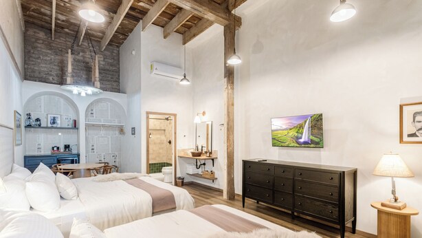 A spacious bedroom with two beds, a wooden dresser, a vanity, and a dining area.