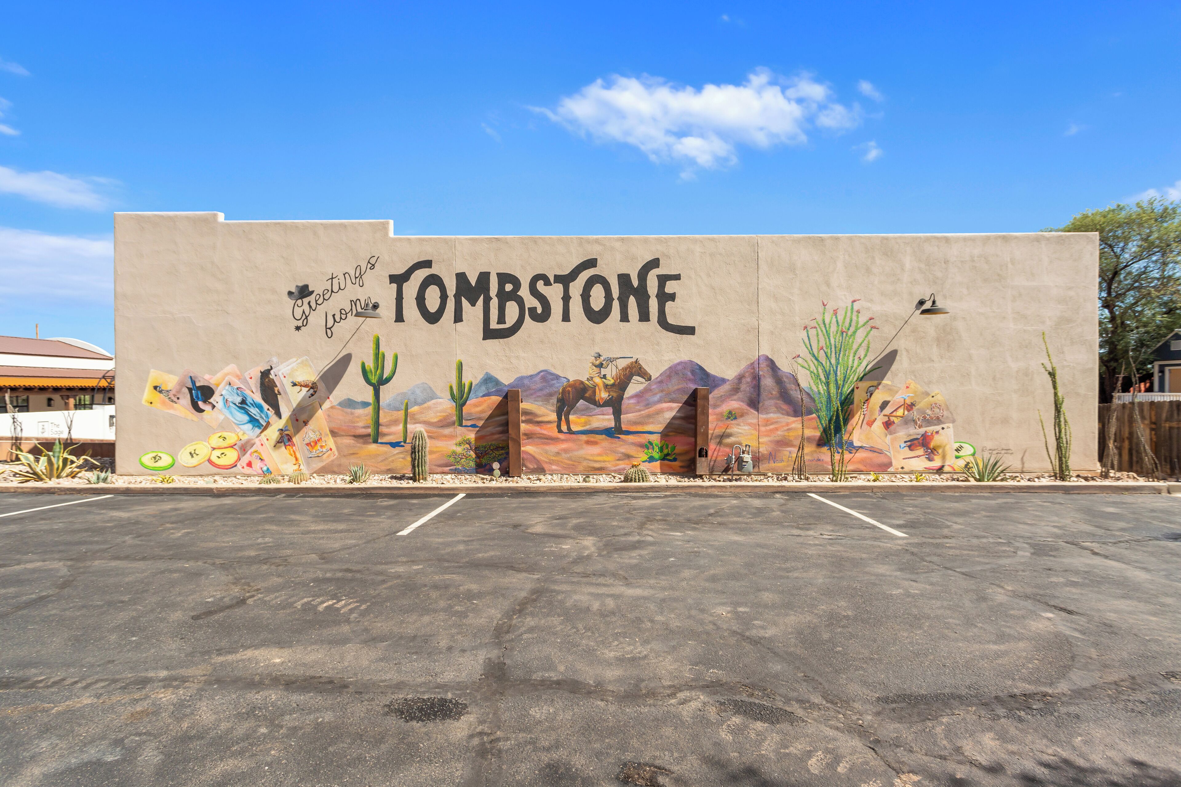 Un mural en un edificio con el texto 'Greetings from Tombstone' y una escena desértica.