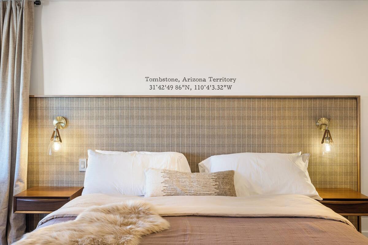 Ein Hotelzimmer mit einem großen Bett, zwei Nachttischen und einem Kopfteil mit einer Plakette, die den Ort Tombstone, Arizona Territory, angibt.