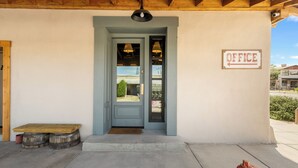 A building entrance with a wooden bench, a door labeled "OFFICE," and a sign indicating the direction to the office.