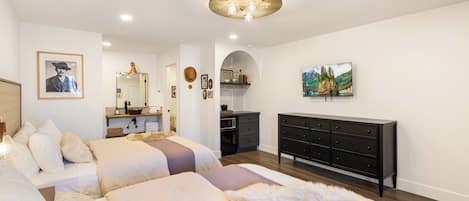 Une chambre avec deux lits, une commode, une coiffeuse avec un miroir et un tableau au mur.
