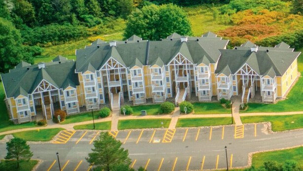A multi-story residential building with a symmetrical facade, a central entrance, and a parking lot in front. - Carriage Studio Retreat (Shanty Bay)