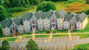 A multi-story residential building with a symmetrical facade, a central entrance, and a parking lot in front.