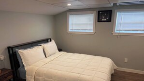 A bedroom with a bed, wooden headboard, two bedside tables, and a nightstand. - Private Penthouse Studio (Providence)