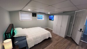 Een slaapkamer met een bed, nachtkastje, televisie en een kledingkast.