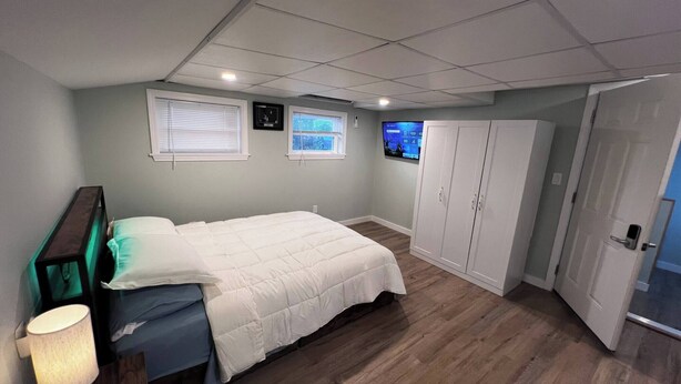 A bedroom with a bed, a nightstand, a TV, and a wardrobe. - Private Penthouse Studio (Providence)