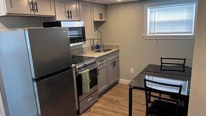 A compact kitchen with a refrigerator, oven, microwave, and granite countertop. - Private Penthouse Studio (Providence)