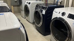 Een wasserette met meerdere wasmachines en drogers, leidingen en elektrische panelen.