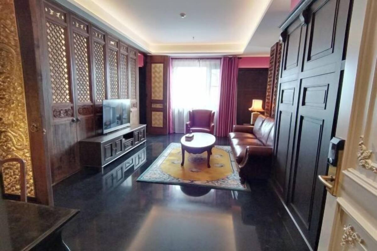 A spacious living room with a television, a coffee table, a sofa, and a decorative rug.