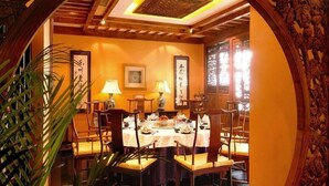 A traditional dining room with a round table, chairs, and a decorative archway. - Auspicious Business (Beijing)