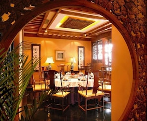 A traditional dining room with a round table, chairs, and a decorative archway. - Auspicious Business (Beijing)