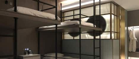 Habitación con literas, ventana circular empotrada, mesita de noche y perchero.