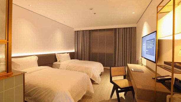 A hotel room with two beds, a desk, a television, and a window with curtains. - Auspicious Business (Beijing)