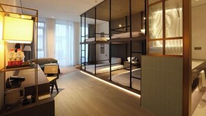 Een moderne hotelkamer met een stapelbed, een bureau met lamp en een groot raam.