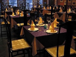 A restaurant with tables set for dining, featuring gold-colored chairs and purple tablecloths. - Auspicious Business (Beijing)