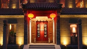Een traditioneel Chinees gebouw met een houten inkom, verlicht door lantaarns, en met grote Chinese karakters op de deuren.
