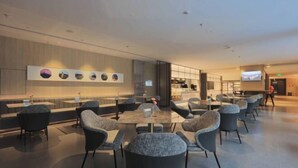 Een moderne lounge met een lange bank en meerdere tafels en stoelen.