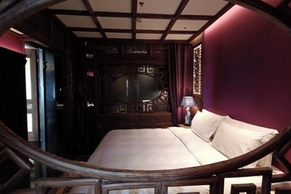 A circular room with a bed, wooden furniture, and a decorative mirror.