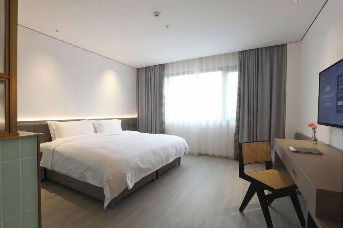 A modern hotel room with a large bed, a desk, and a chair.