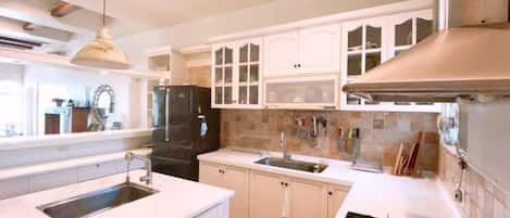 A kitchen with white cabinets, a black refrigerator, a sink, and a stove.