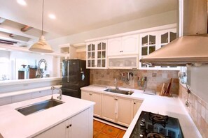 Una cocina con armarios blancos, un refrigerador negro, un fregadero y una estufa.