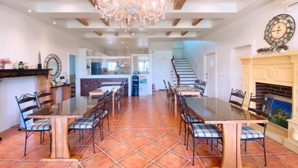 A spacious dining area with a large wooden table and chairs, a chandelier, and a fireplace. - Isa Butterfly Kids B&B (Yilan)