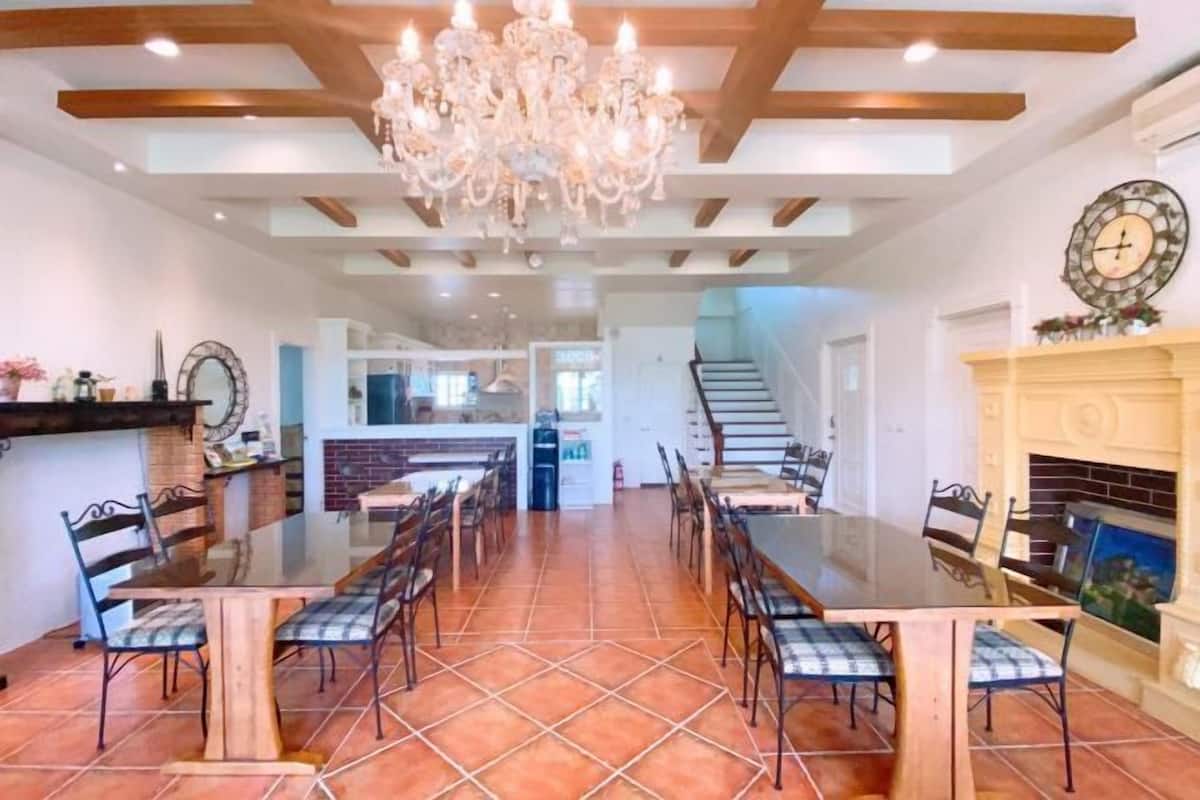 A spacious dining area with a large wooden table and chairs, a chandelier, and a fireplace.