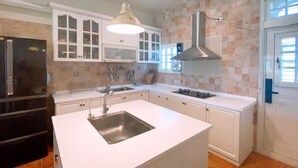 A kitchen with white cabinets, a black refrigerator, a stainless steel sink, and a pendant light. - Isa Butterfly Kids B&B (Yilan)