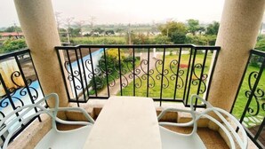 A balcony with a table and chairs, a view of greenery and distant buildings. - Isa Butterfly Kids B&B (Yilan)