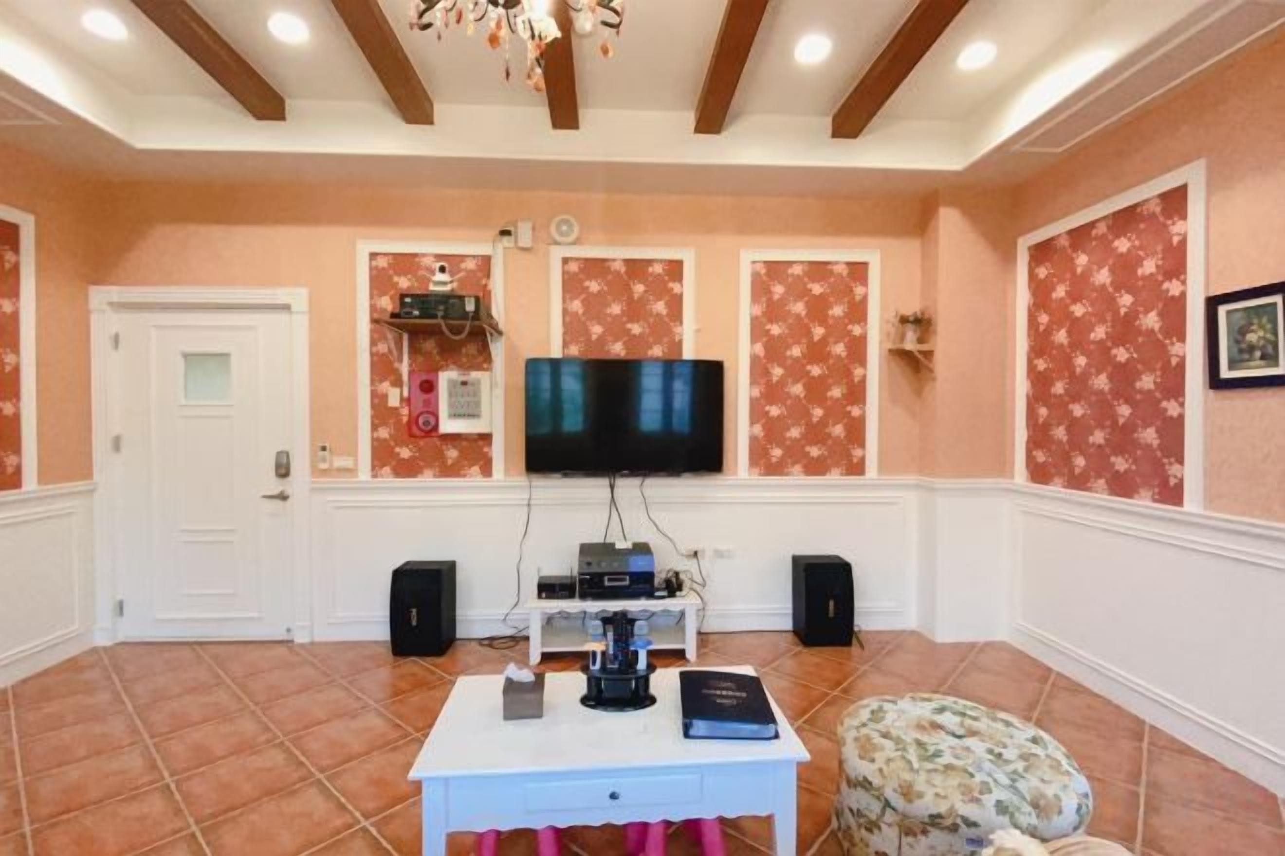 A room with a television, speakers, a coffee machine, and a table with a book.