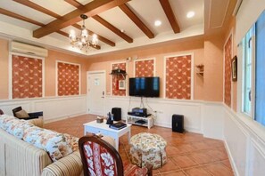 Una sala de estar con sofá, reposapiés, mesa de centro y televisor.