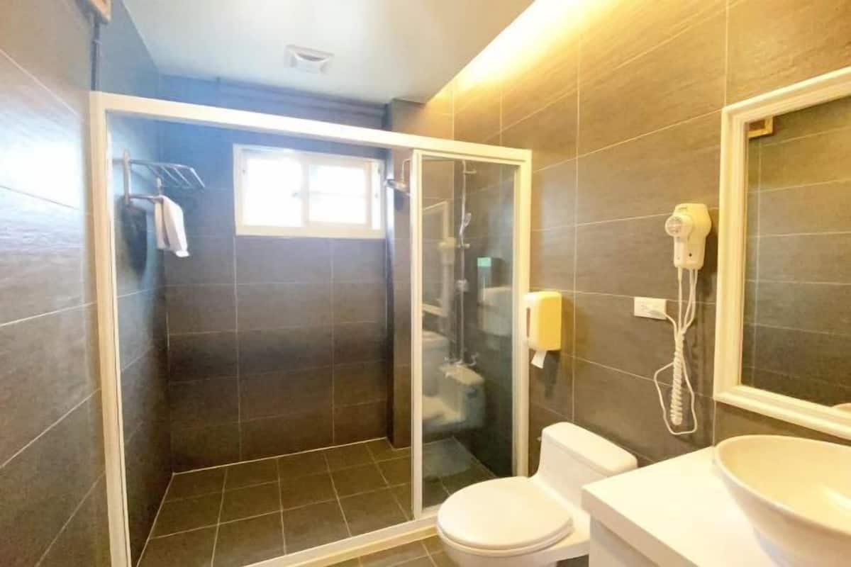 A bathroom with a glass-enclosed shower, a toilet, and a sink with a mirror.