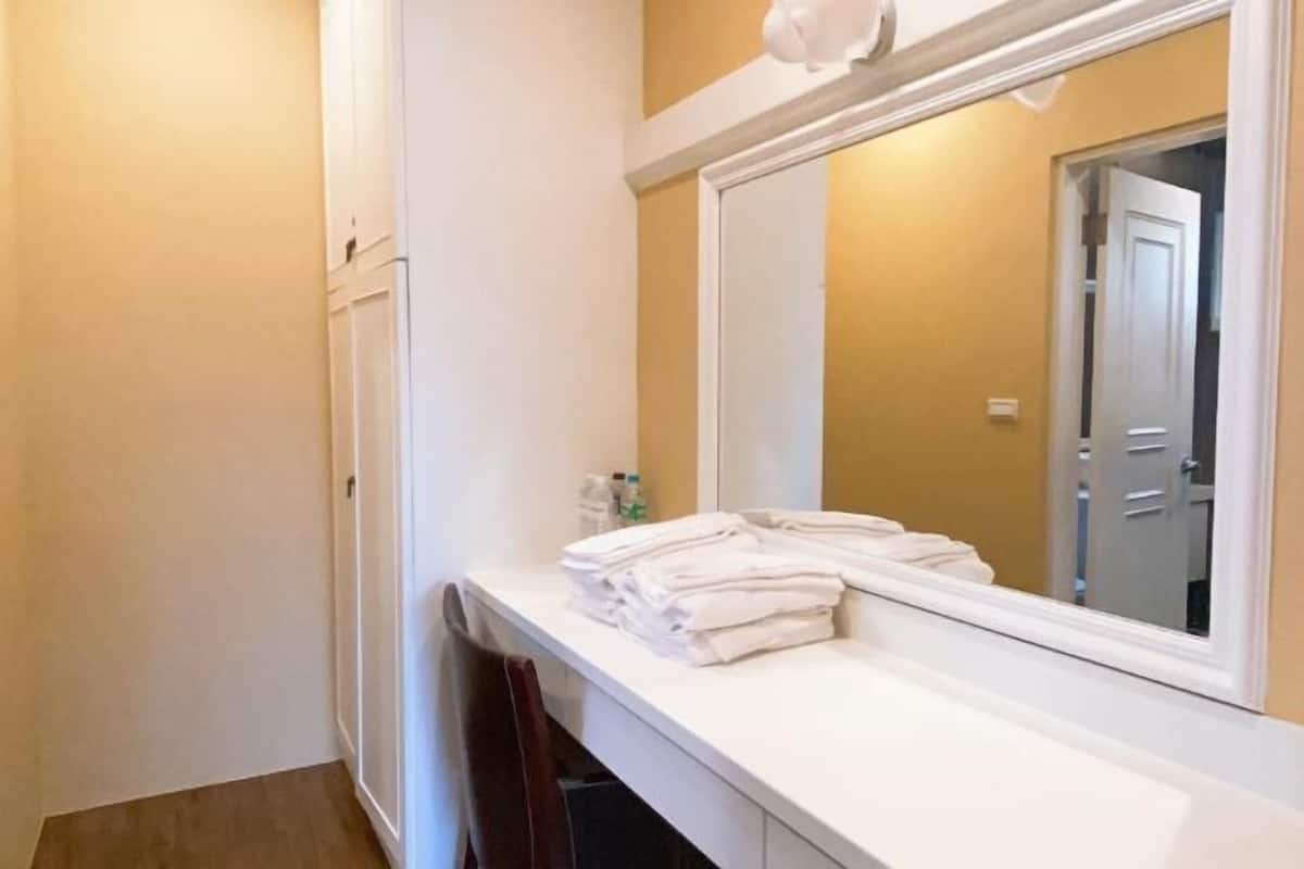 A bathroom with a white vanity, a mirror, and a towel stack.