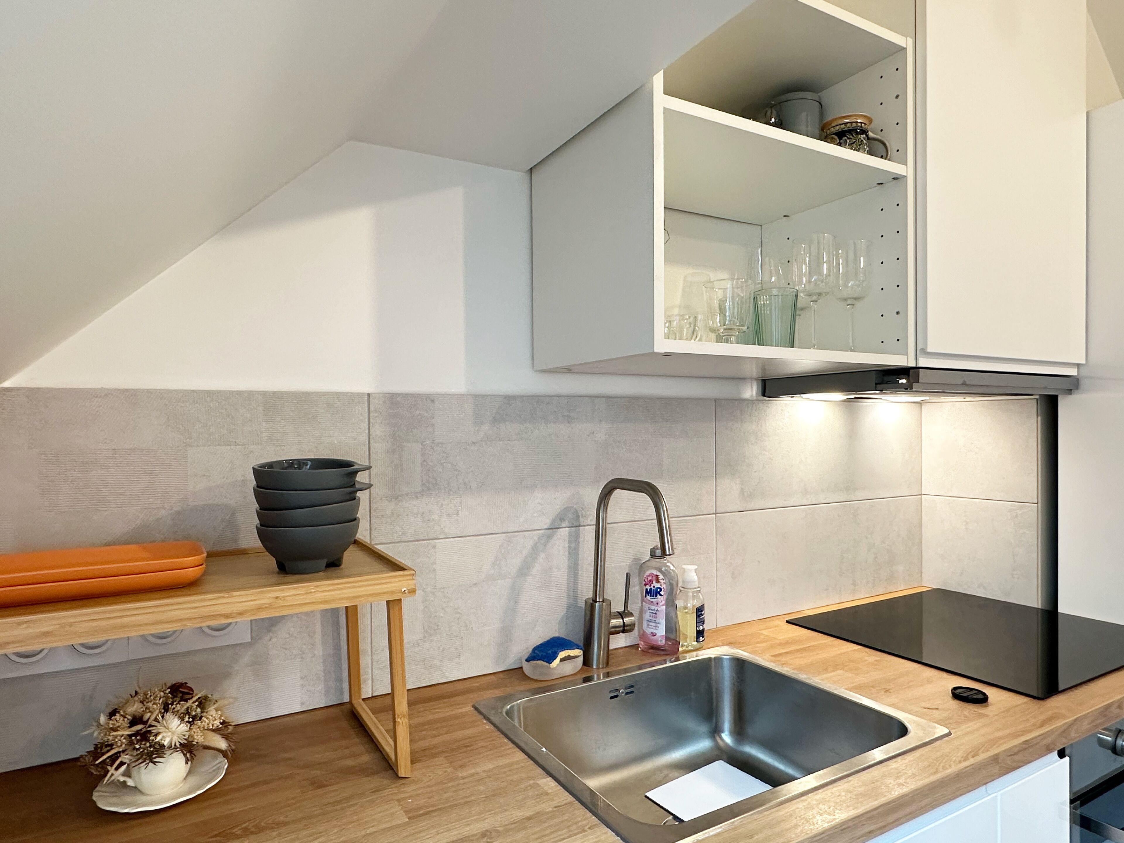 A modern kitchen with a stainless steel sink, wooden countertop, and a built-in oven.