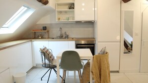 A compact kitchen with a skylight, a dining area with a chair, and a small table. - Lovely Rooftop designed Apt 200m to Panthéon  (Paris)