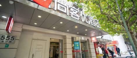 A hotel entrance with a signboard, a revolving door, and a visible entrance door.