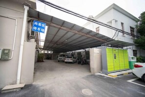 Un parcheggio con ingresso coperto, un deposito verde e un'auto bianca all'interno.