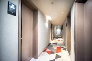 A hotel corridor with doors on both sides, a patterned floor, and a light fixture on the ceiling. - Shankee Hotel (Shanghai Jiading Jinsha Road) (Shanghai)