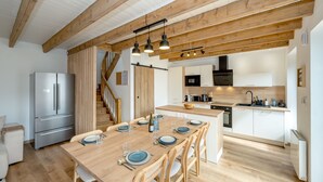 Eine moderne Küche mit Holzbalken, einer zentralen Kochinsel und einem eingebauten Backofen.