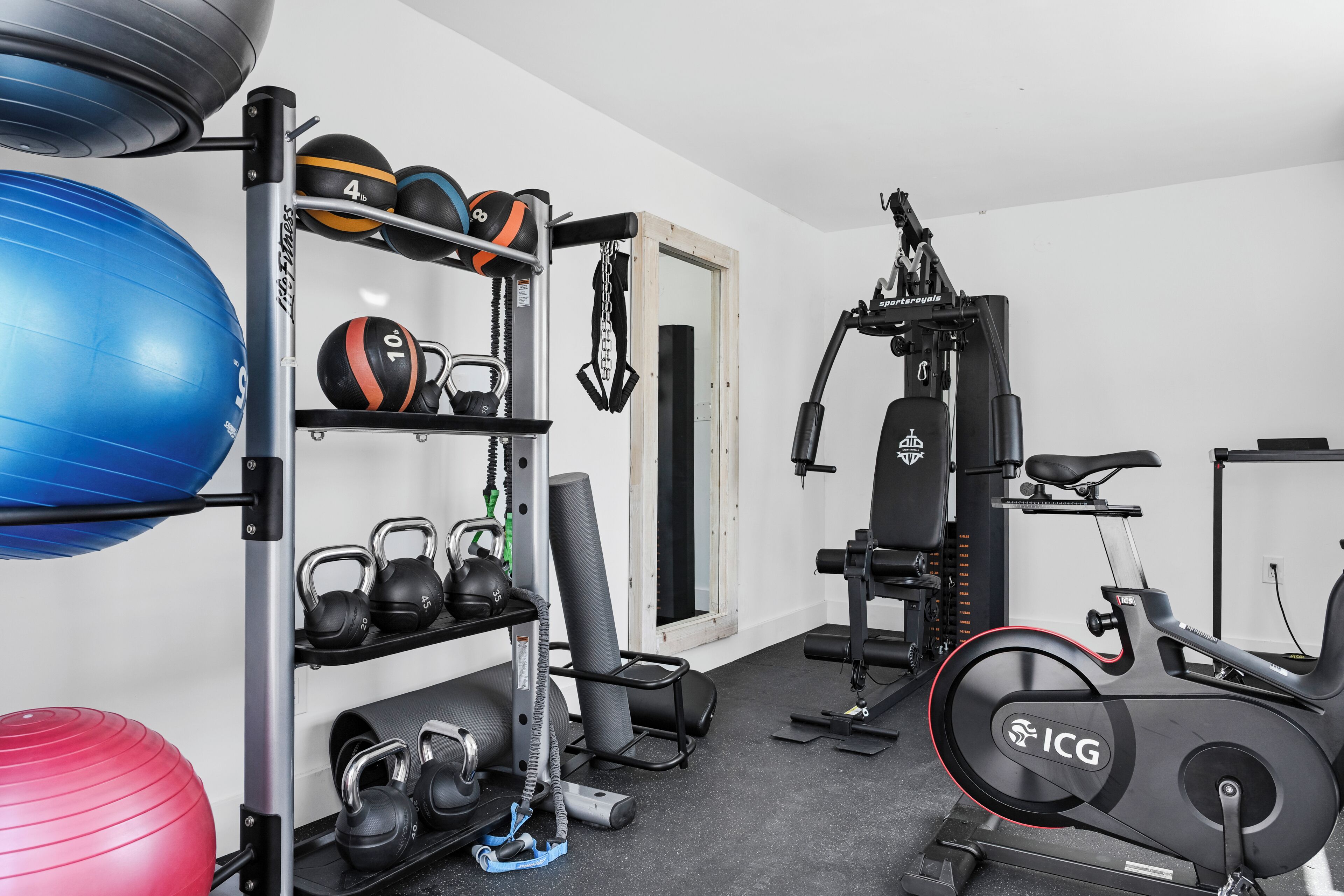 A home gym with exercise equipment, including a stationary bike, kettlebells, and exercise balls.