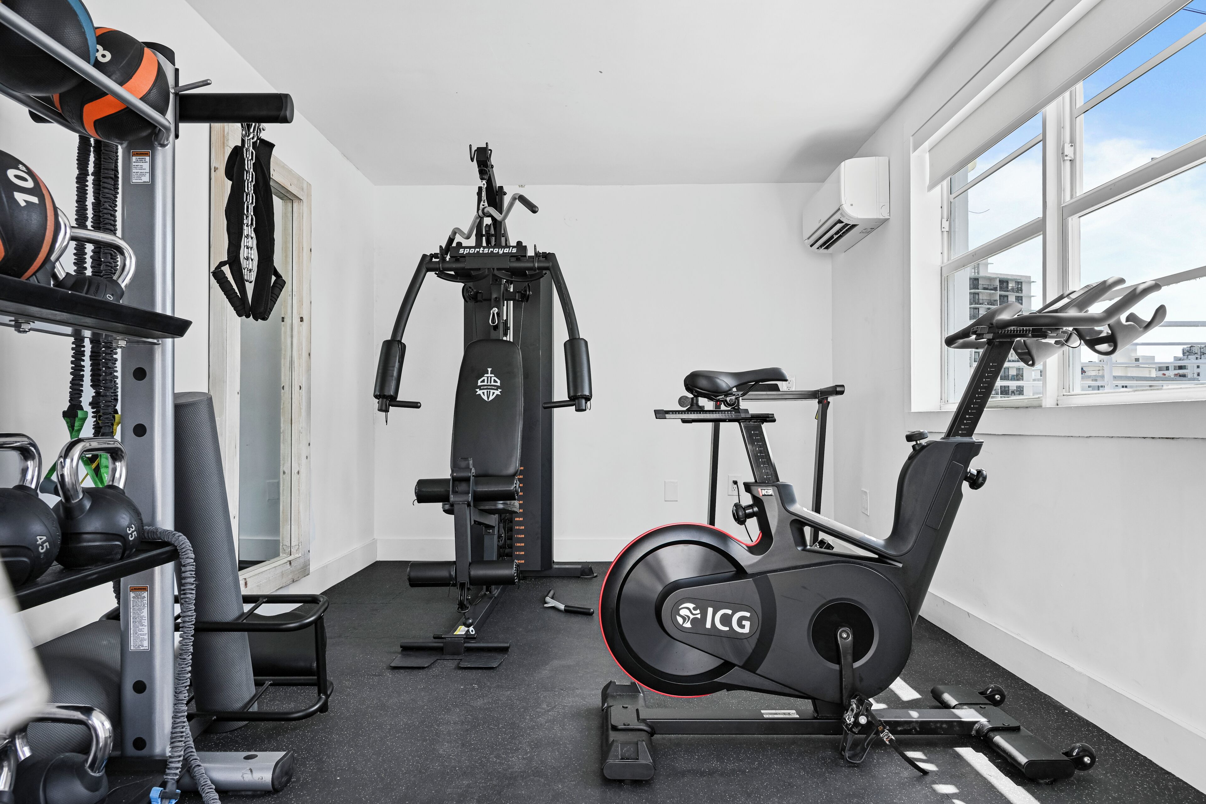 A gym with exercise equipment, a treadmill, and a window with a city view.