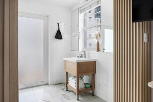 A bathroom with a white sink, wooden vanity, and a mirror.