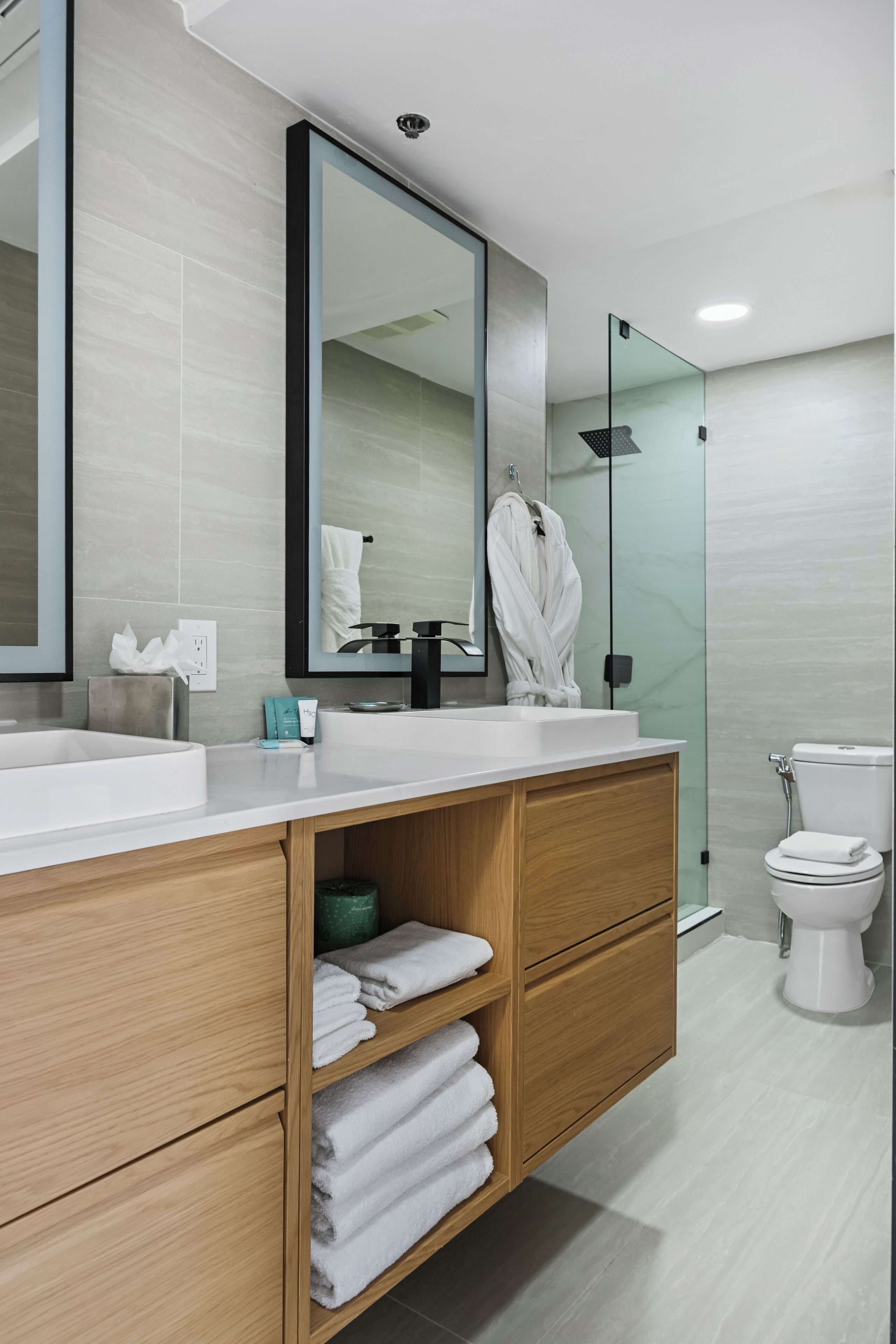 Une salle de bain moderne avec un grand miroir, deux lavabos, une douche et des toilettes.