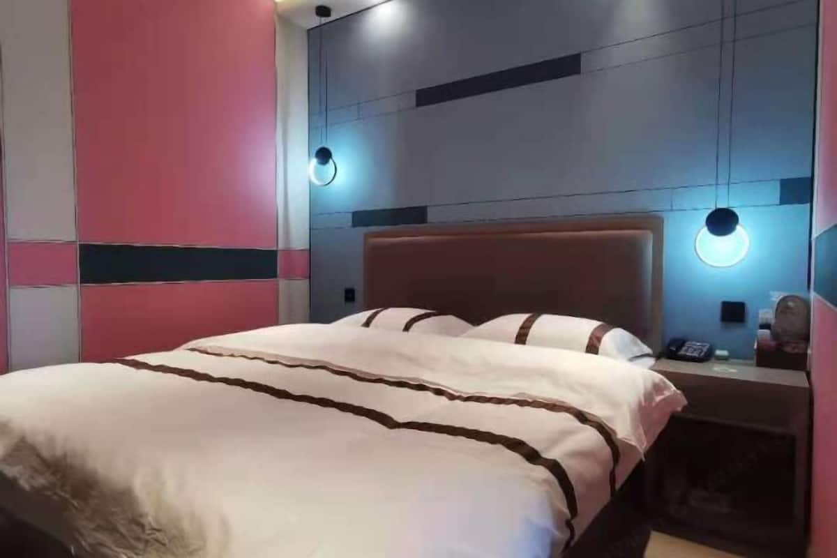 Habitación de hotel con cama, mesitas de noche e iluminación empotrada.