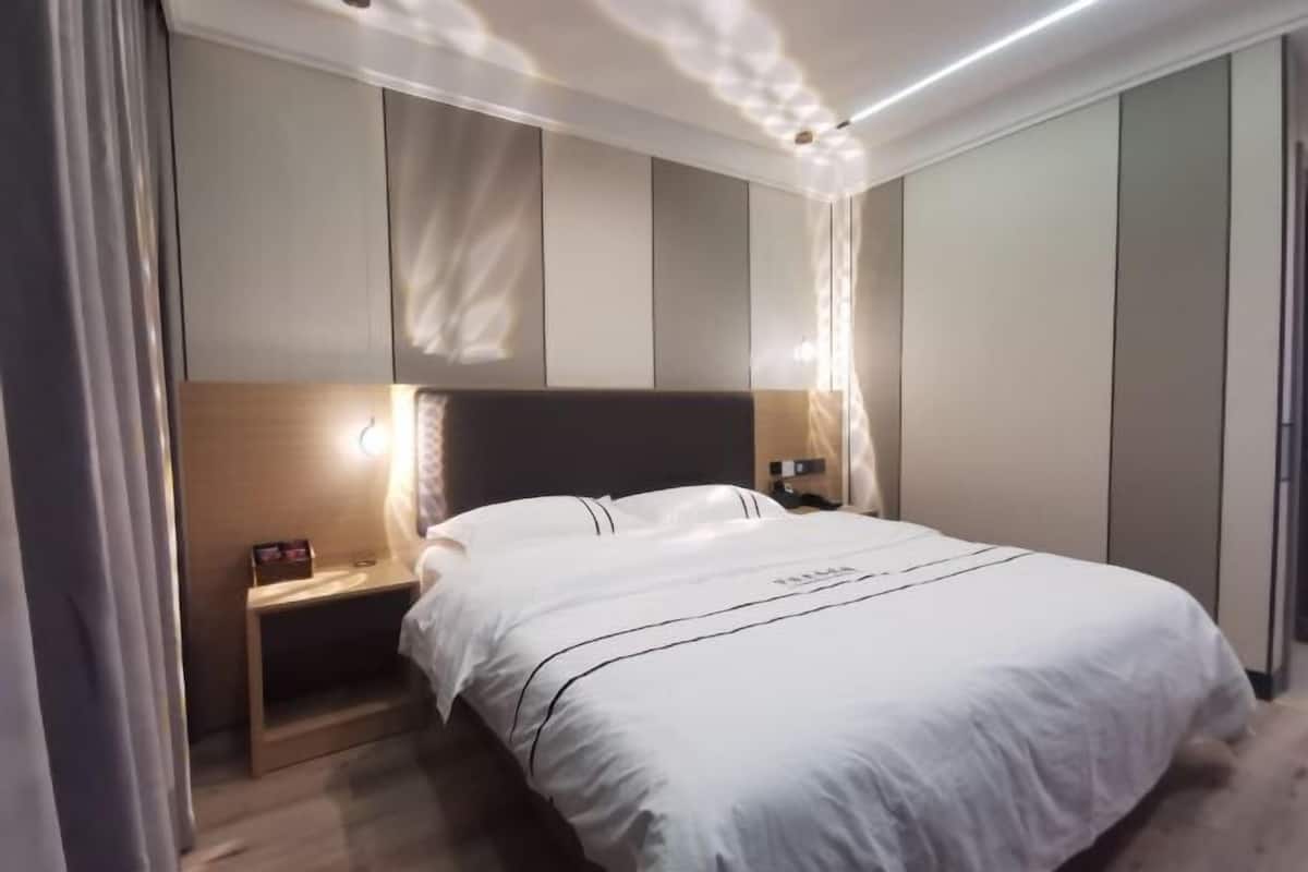 Un dormitorio moderno con cama, mesitas de noche y velador.