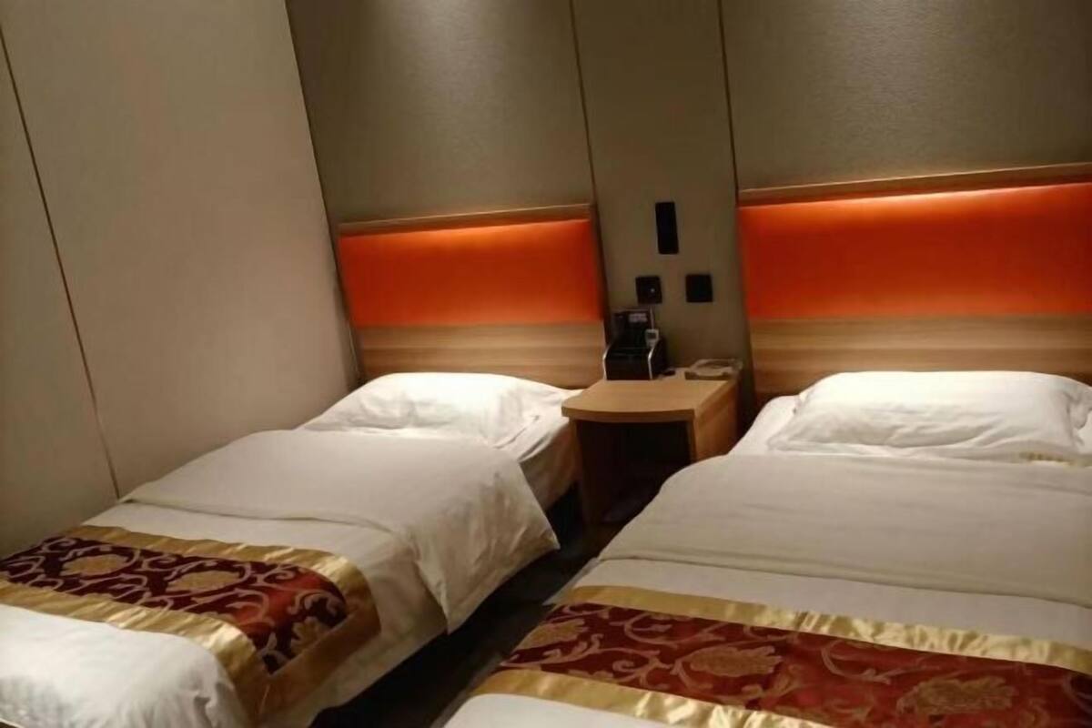 Habitación de hotel con dos camas, una mesita de noche y teléfono en la pared.