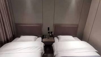 A hotel room with two beds, a nightstand, and a wall-mounted phone.