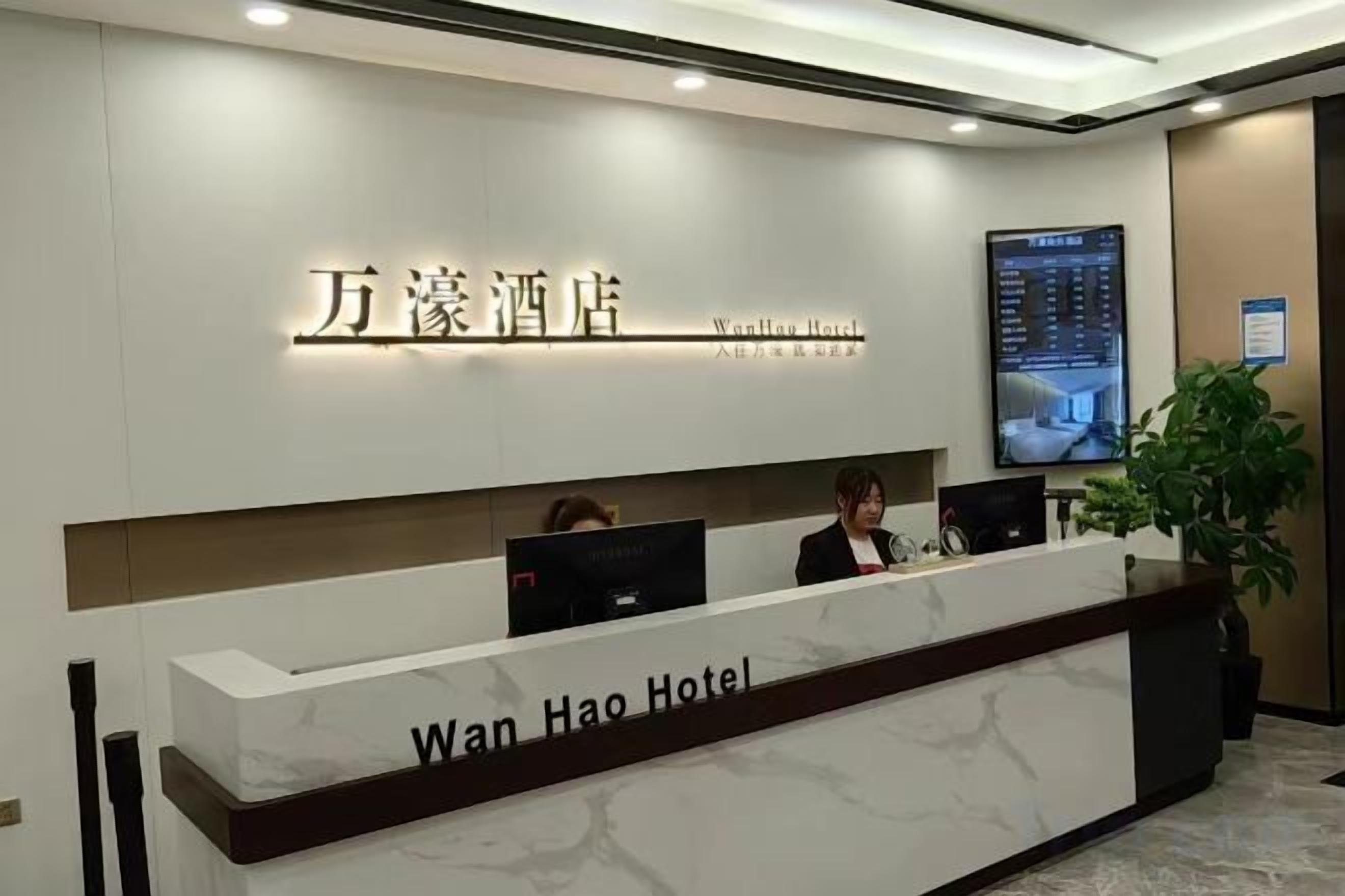 A hotel reception desk with a digital display and a reception area.