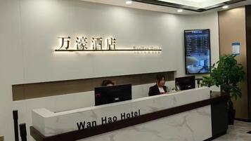 A hotel reception desk with a digital display and a reception area.