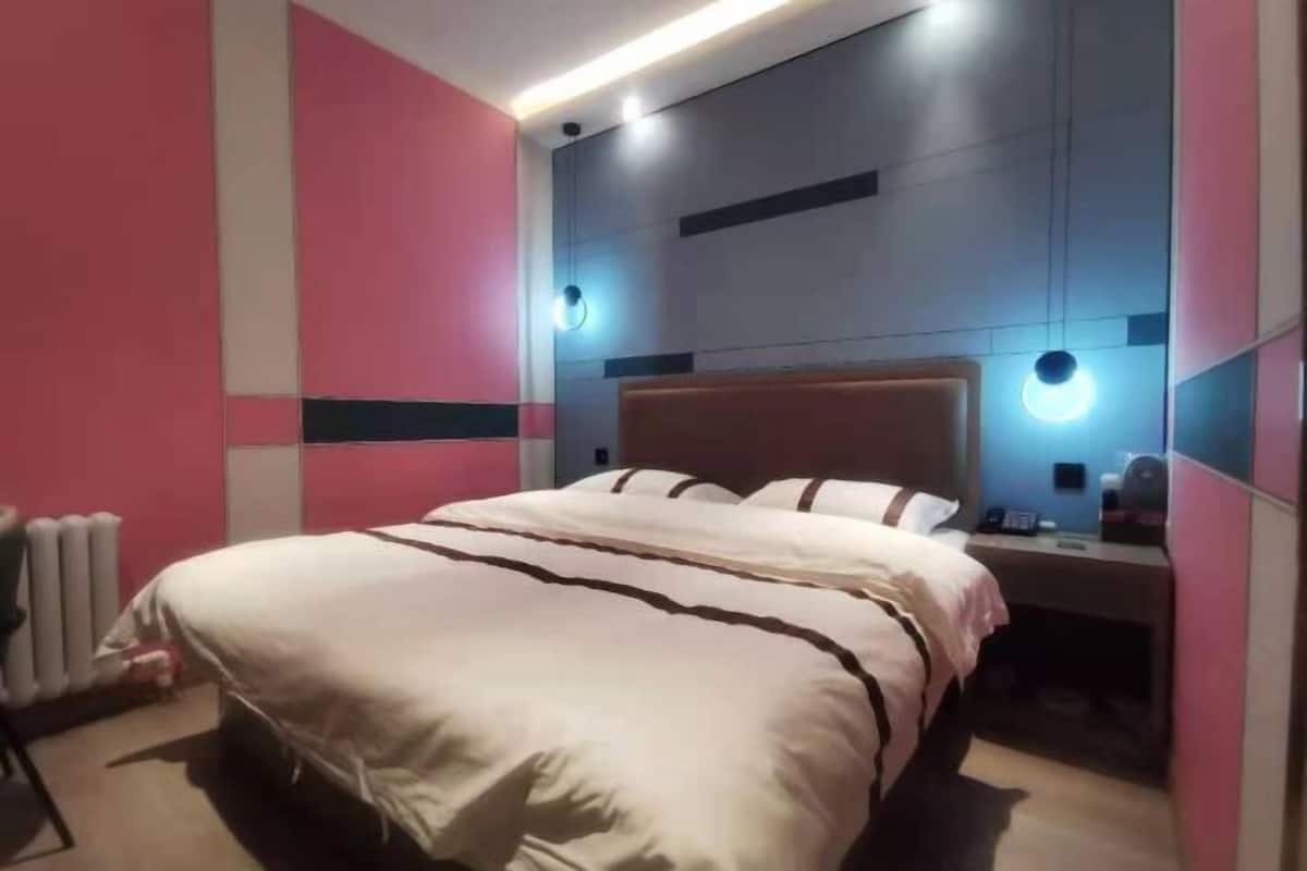 Una habitación de hotel moderna con cama, mesita de noche e iluminación empotrada.